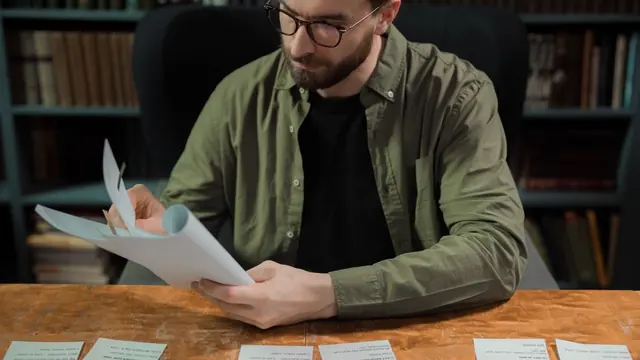 Student sorting handwritten flashcards at a wooden desk in a library