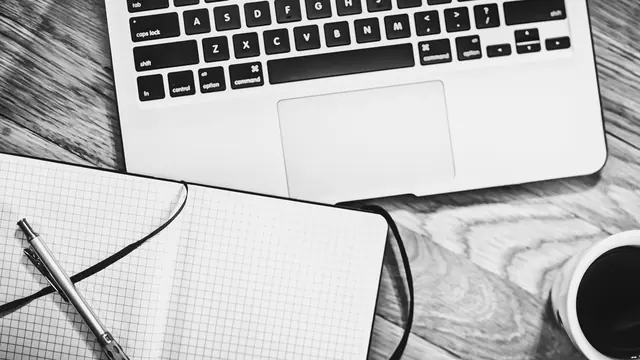 Laptop, notebook, pen and coffee on a wooden desk