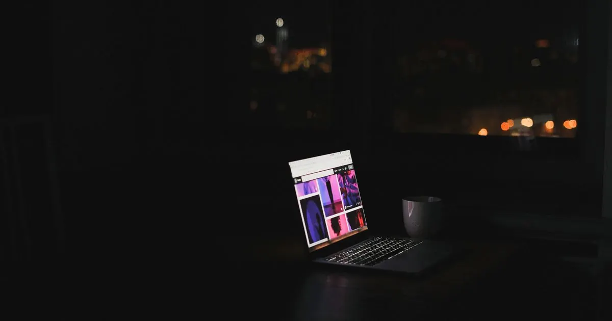 Laptop glowing on a desk in a dark room at night