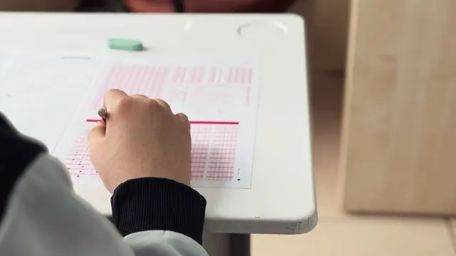 Student filling in answer bubbles on a multiple-choice answer sheet
