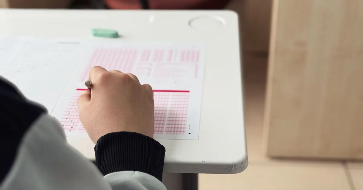 Student filling in answer bubbles on a multiple-choice answer sheet