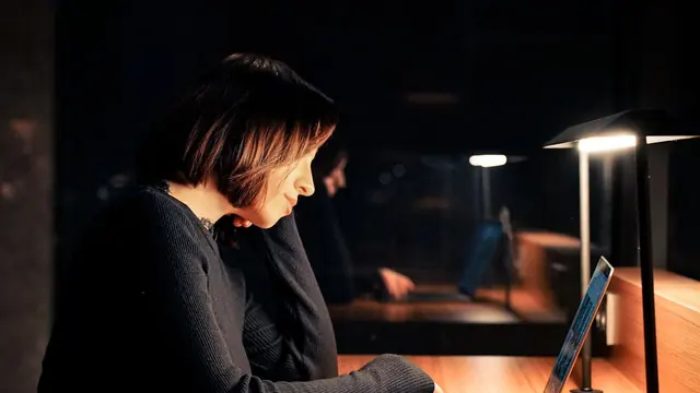 Student studying on a laptop late at night under a desk lamp