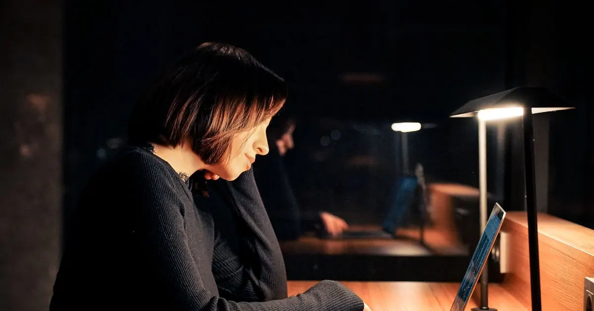 Student studying on a laptop late at night under a desk lamp
