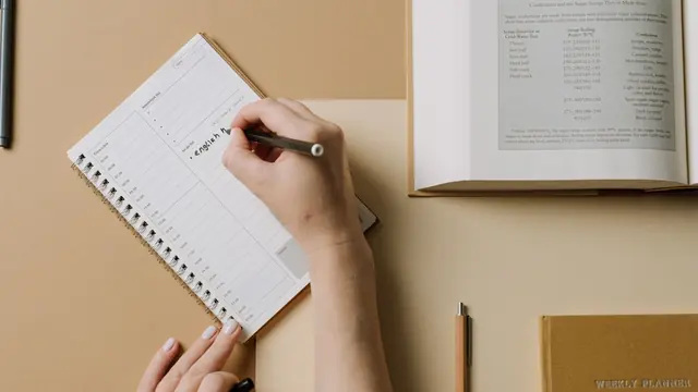 Hand writing a weekly study plan in a spiral notebook