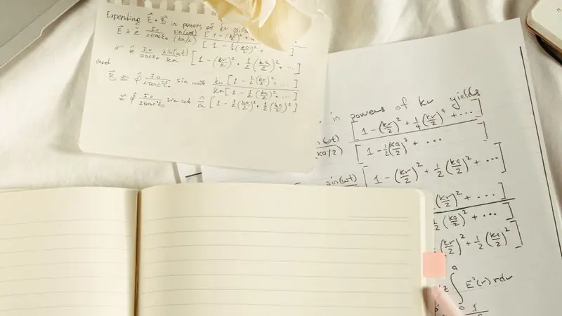 Notebook pages covered in handwritten maths working and formulas